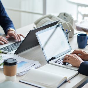 Cropped image of business people working on laptops in office
